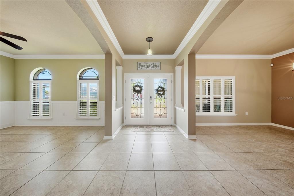 A tiled entryway features double glass-paneled front doors, arched windows with shutters, and crown molding — 354 HOPE BAY LOOP, APOLLO BEACH, FL