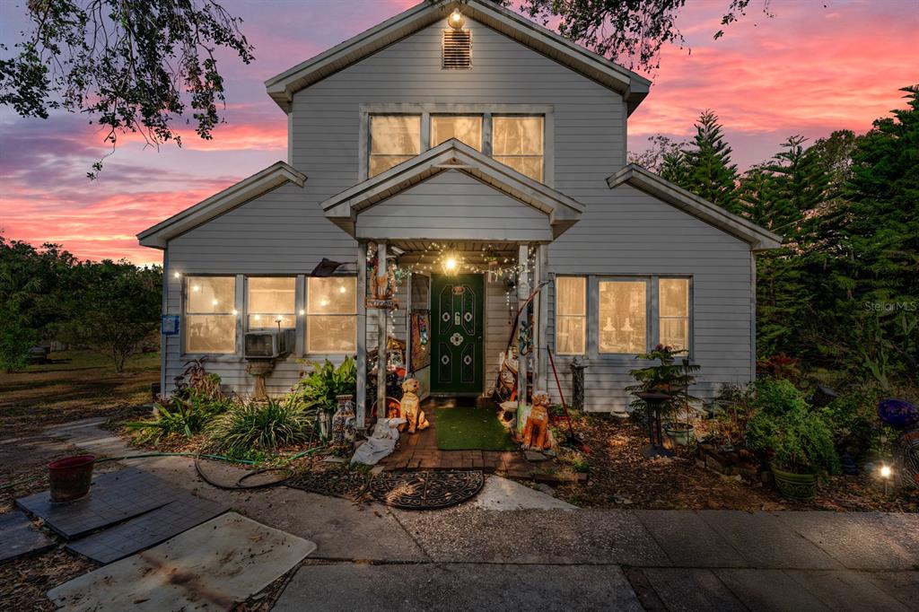 A two-story house with light gray siding and a green front door at sunset — 9602 RIPLEY ROAD, THONOTOSASSA, FL