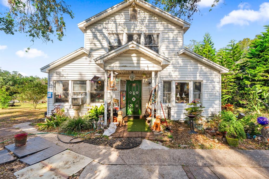 A two-story white wood-sided house features a green front door and a covered porch — 9602 RIPLEY ROAD, THONOTOSASSA, FL