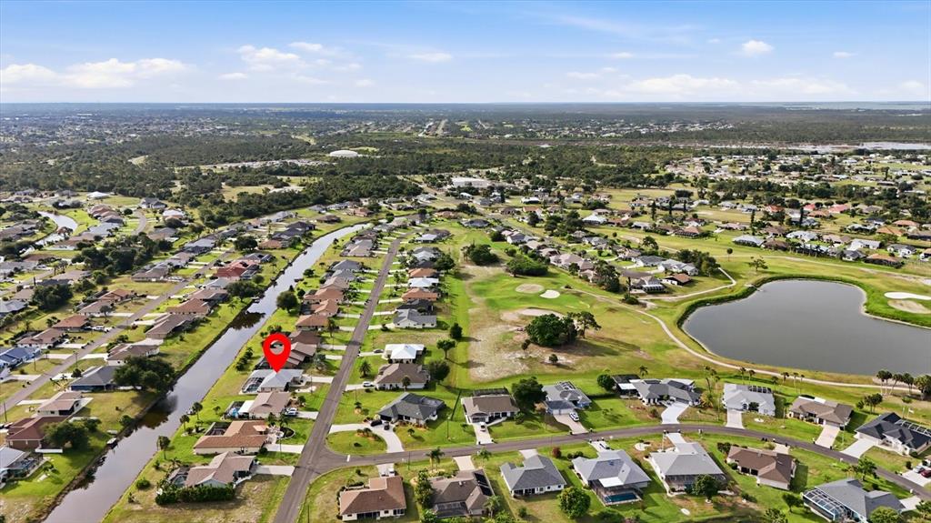 An aerial view shows a residential neighborhood with a canal, a golf course, and a lake — 175 BUNKER ROAD, ROTONDA WEST, FL