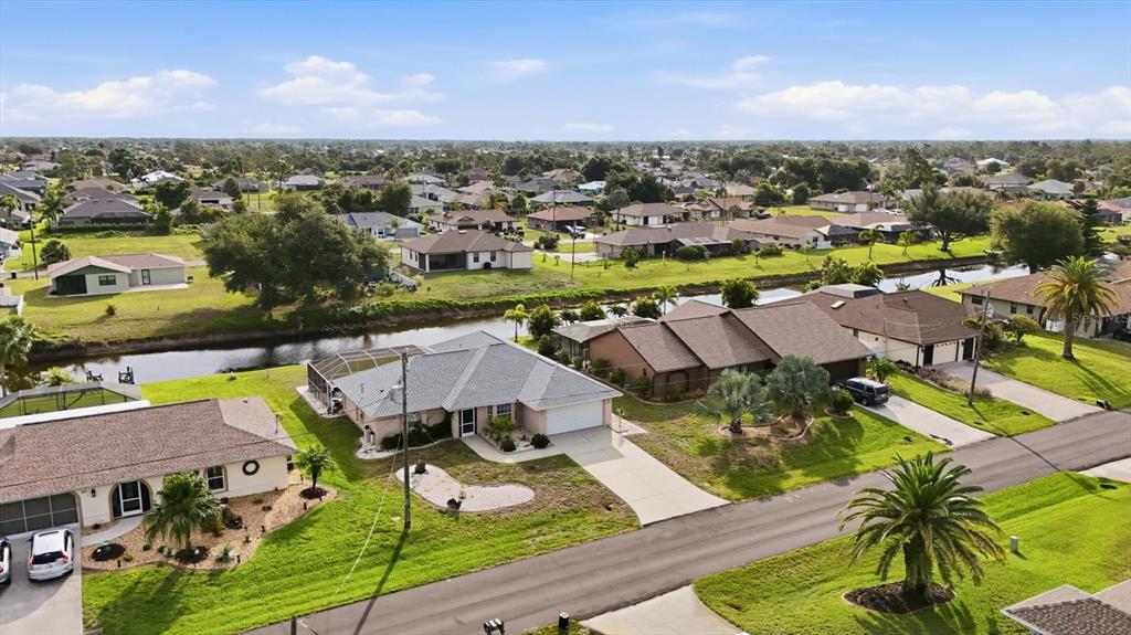 An aerial view shows several suburban houses with driveways and backyards bordering a narrow canal — 175 BUNKER ROAD, ROTONDA WEST, FL
