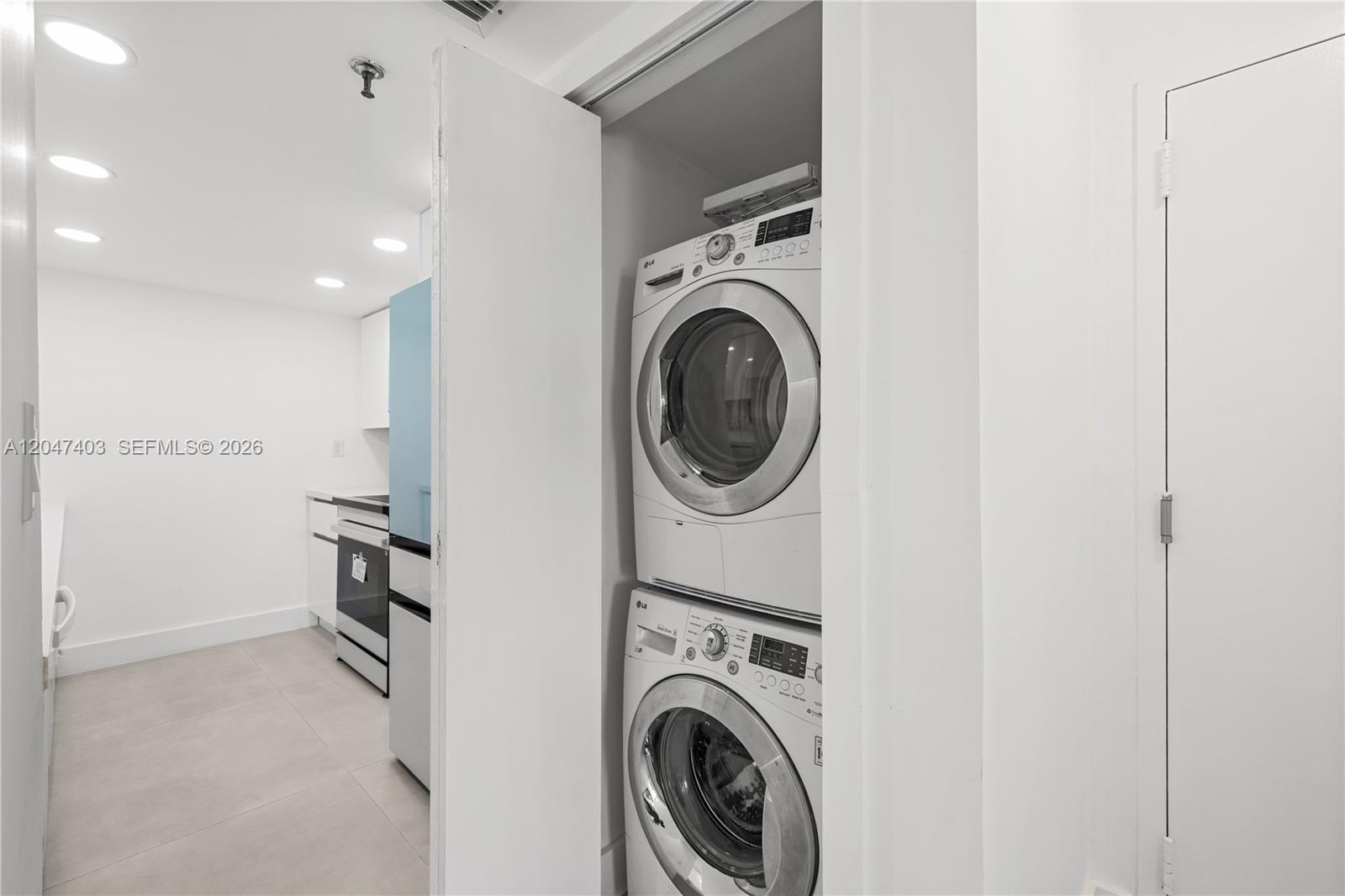 A stacked washer and dryer unit sits in a closet next to a modern kitchen — 2457 Collins Ave # 201, Miami Beach FL 33140, MIAMI BEACH, FL