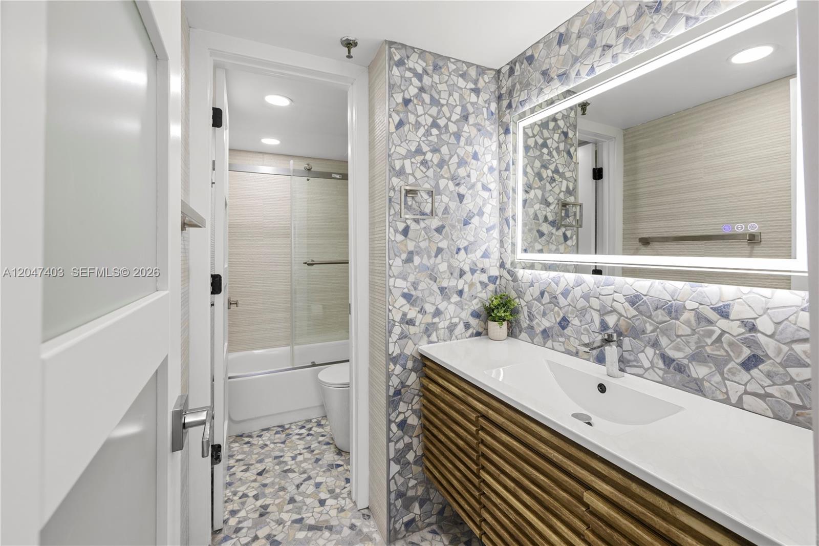 A bathroom features a mosaic tile wall, a floating wood vanity, and a separate shower area — 2457 Collins Ave # 201, Miami Beach FL 33140, MIAMI BEACH, FL
