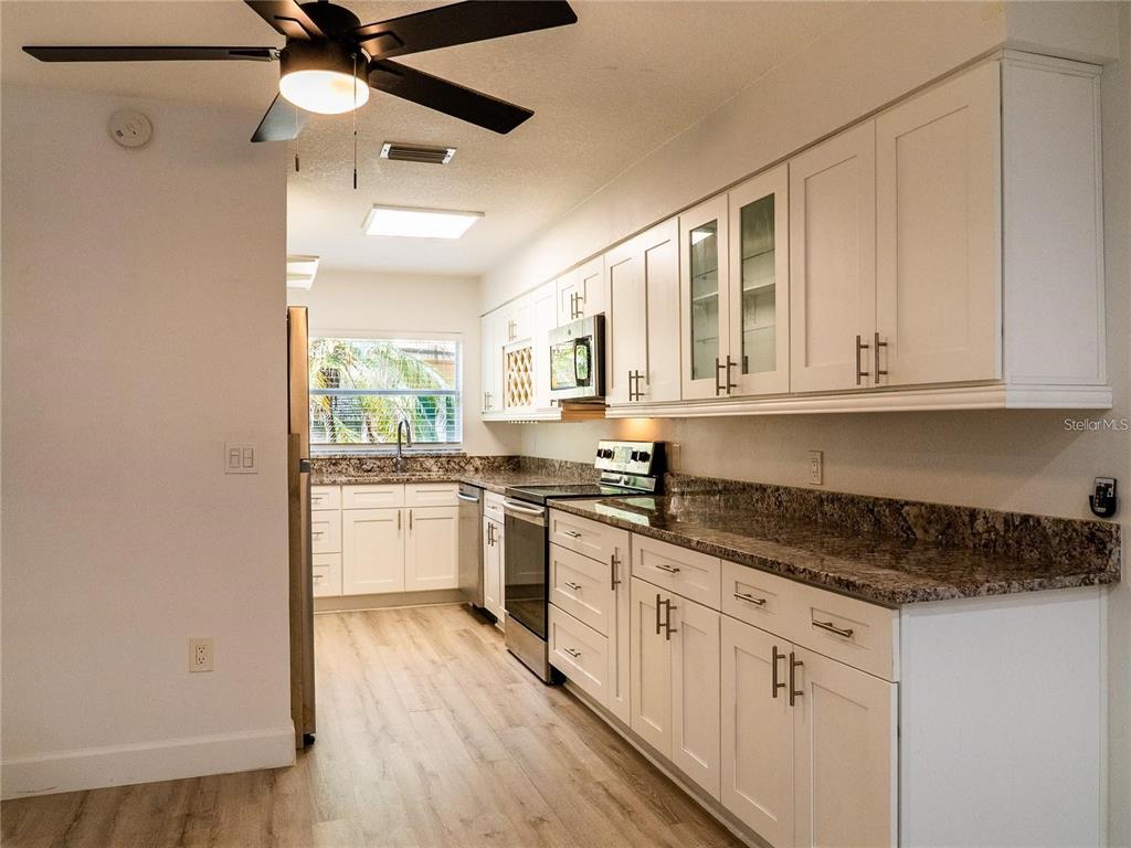 A kitchen features white shaker cabinets, granite countertops, stainless steel appliances, and wood-look flooring — 517 S SUMMERLIN AVENUE, ORLANDO, FL