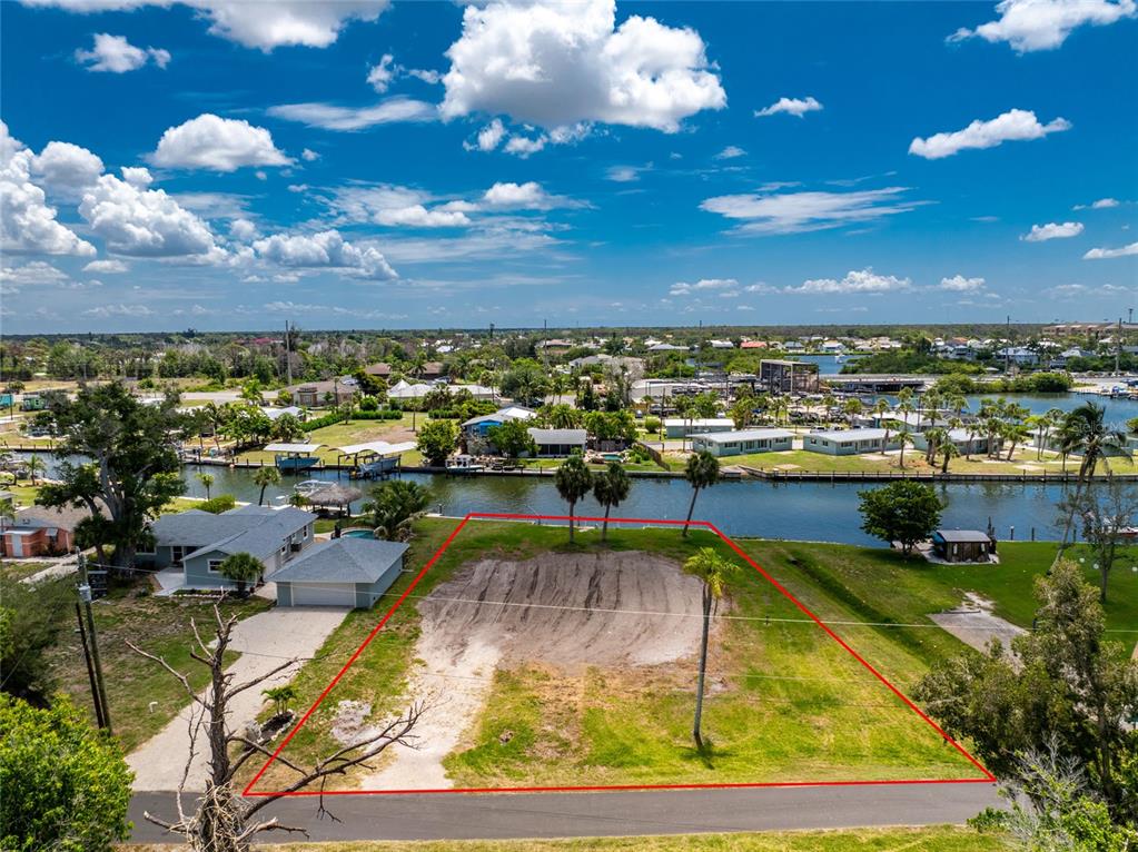 An aerial view shows a vacant waterfront lot outlined in red next to a house — 1899 RIVERSIDE DRIVE, ENGLEWOOD, FL