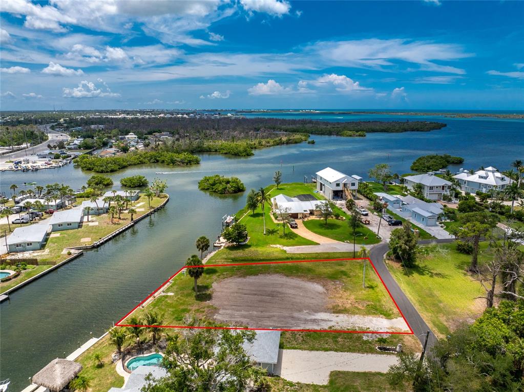 An aerial view shows a vacant, rectangular waterfront lot outlined in red near a canal — 1899 RIVERSIDE DRIVE, ENGLEWOOD, FL