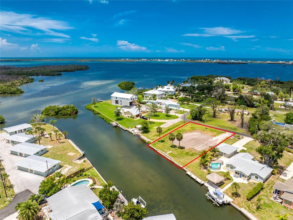 An aerial view shows a vacant waterfront lot outlined in red along a canal — 1899 RIVERSIDE DRIVE, ENGLEWOOD, FL