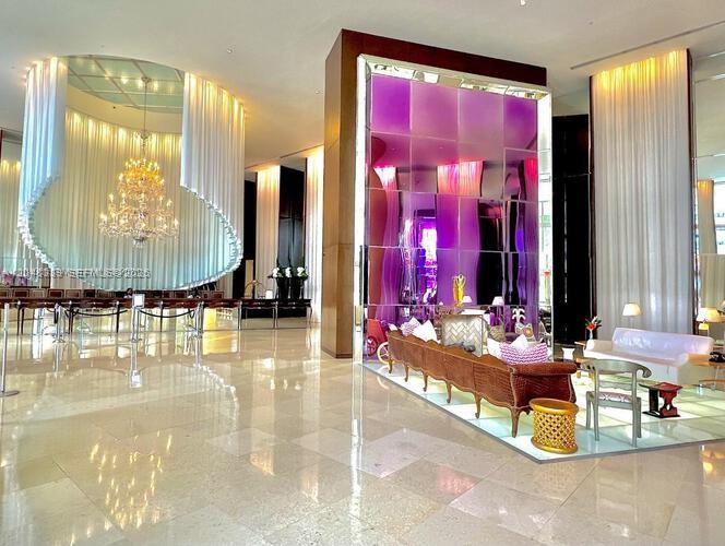 A modern hotel lobby features a large crystal chandelier, purple glass partitions, and white curtains — 450 Alton Rd # 1606, Miami Beach FL 33139, MIAMI BEACH, FL