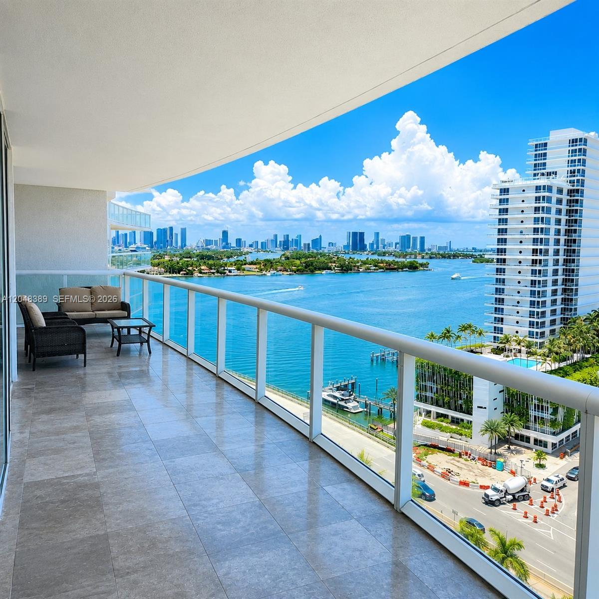 A tiled balcony with outdoor furniture overlooks a bay, a marina, and a city skyline — 450 Alton Rd # 1606, Miami Beach FL 33139, MIAMI BEACH, FL