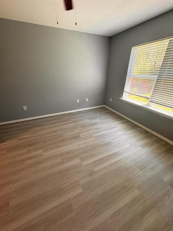 An empty bedroom with gray walls, light wood-look flooring, and a window with blinds — 4266 DUTCHESS PARK ROAD, FORT MYERS, FL