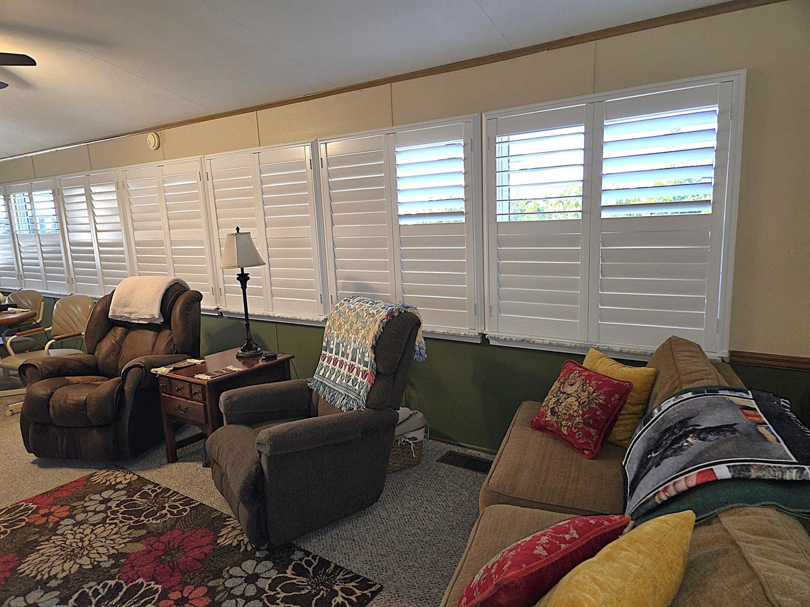 A living room features a brown sofa, two recliners, and white plantation shutters on the windows — 14041 SE 126th Boulevard # 62, Okeechobee FL 34974, OKEECHOBEE, FL