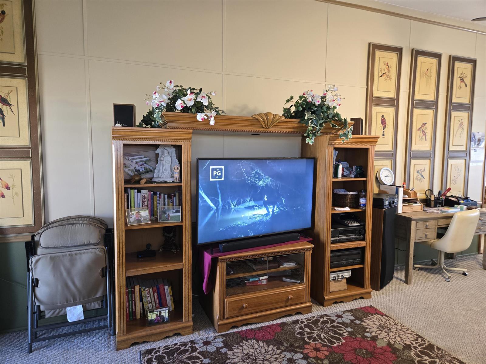 A living room features a wooden entertainment center with a television and adjacent desk area — 14041 SE 126th Boulevard # 62, Okeechobee FL 34974, OKEECHOBEE, FL