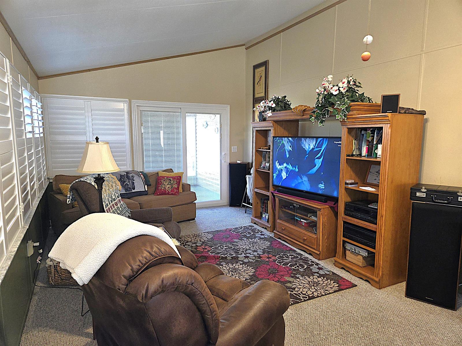 A living room features a large wooden entertainment center, a brown recliner, and a sofa — 14041 SE 126th Boulevard # 62, Okeechobee FL 34974, OKEECHOBEE, FL