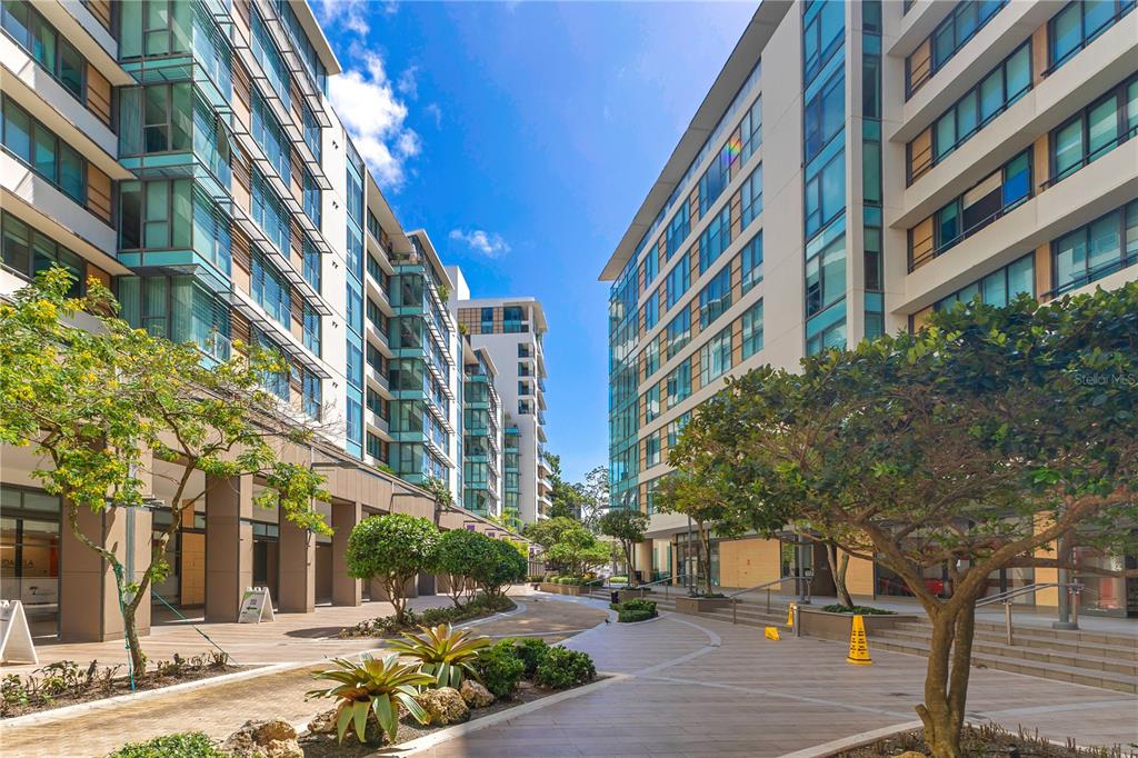 A paved outdoor courtyard sits between two modern multi-story apartment buildings with glass balconies — 1511 PONCE DE LEON AVENUE UNIT 923, SANTURCE, PR
