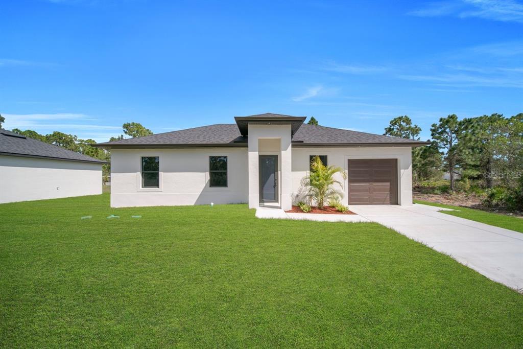 A single-story house with a white stucco exterior, dark roof, and a one-car garage — 637 SUMMIT AVENUE S, LEHIGH ACRES, FL