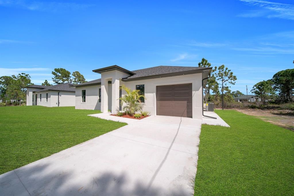 A modern, single-story house with a concrete driveway, a brown garage door, and a grassy yard — 637 SUMMIT AVENUE S, LEHIGH ACRES, FL