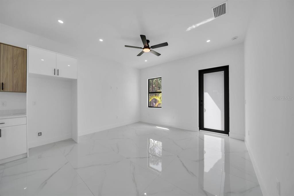 A modern, white-walled room features large marble-look floor tiles, a ceiling fan, and cabinetry — 637 SUMMIT AVENUE S, LEHIGH ACRES, FL