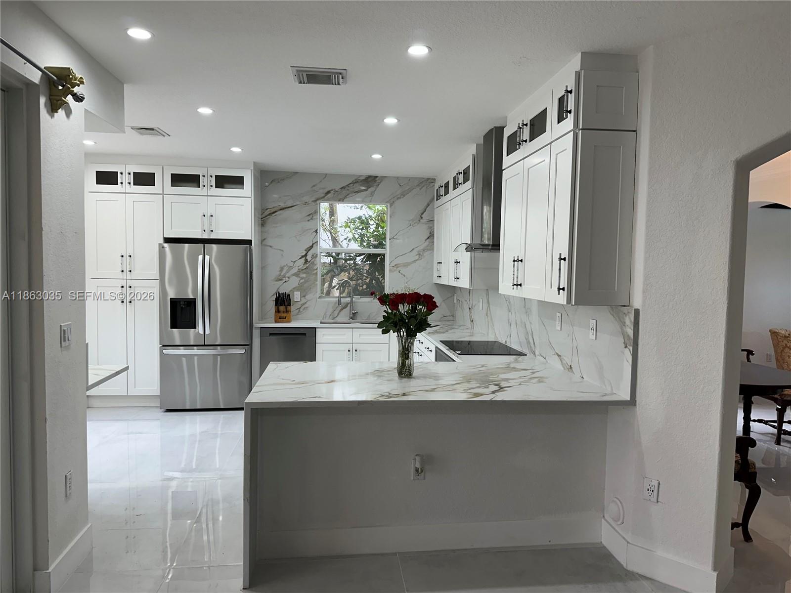 A modern kitchen features white cabinets, marble-patterned countertops, and stainless steel appliances — 6049 SW 165th Ave, Miami FL 33193, MIAMI, FL
