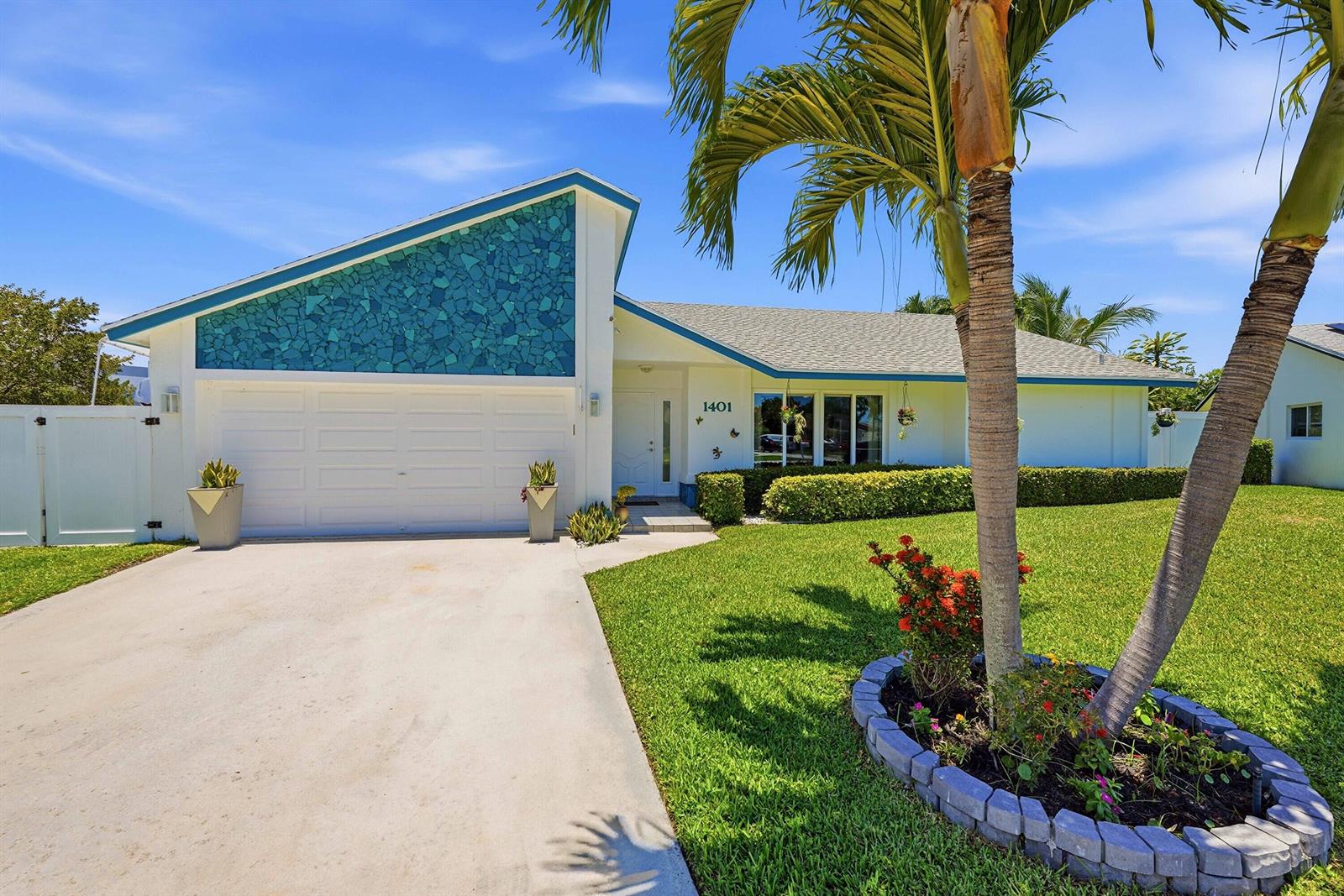 A single-story house with a white garage, blue stone accent wall, and a palm tree — 1401 SW 28th Terrace, Deerfield Beach FL 33442, DEERFIELD BEACH, FL