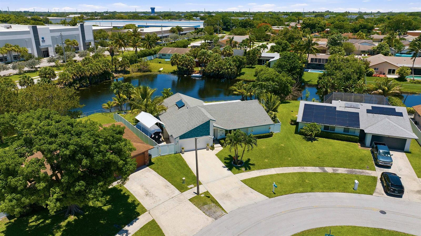 An aerial view shows a suburban house with a gray roof, solar panels, and a pond — 1401 SW 28th Terrace, Deerfield Beach FL 33442, DEERFIELD BEACH, FL
