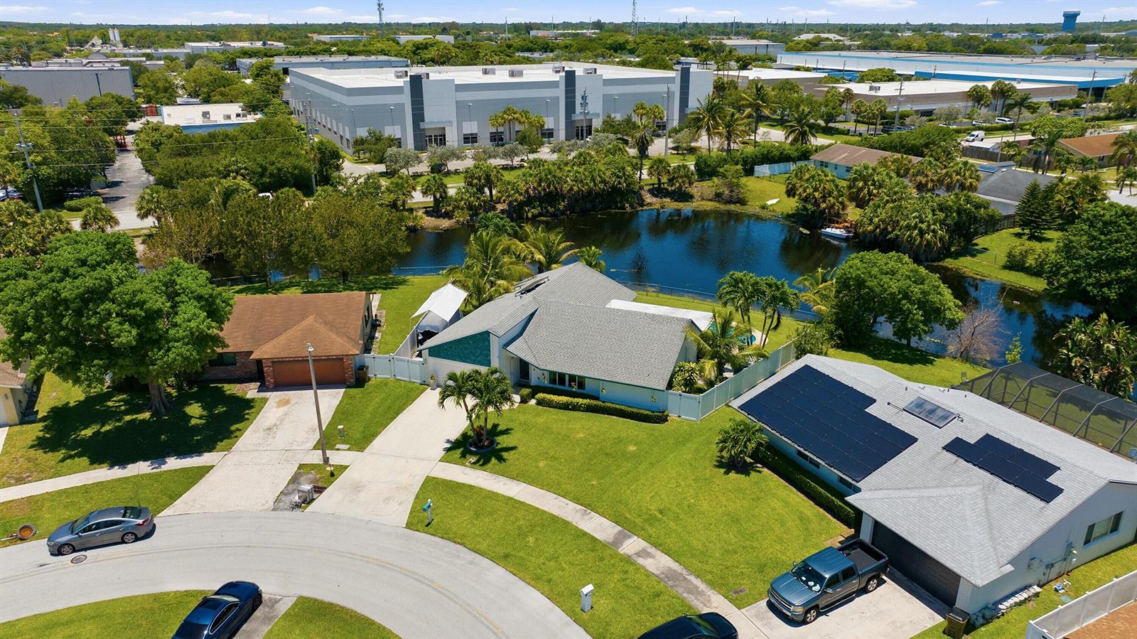 An aerial view shows suburban houses with pools and a pond near industrial warehouses — 1401 SW 28th Terrace, Deerfield Beach FL 33442, DEERFIELD BEACH, FL