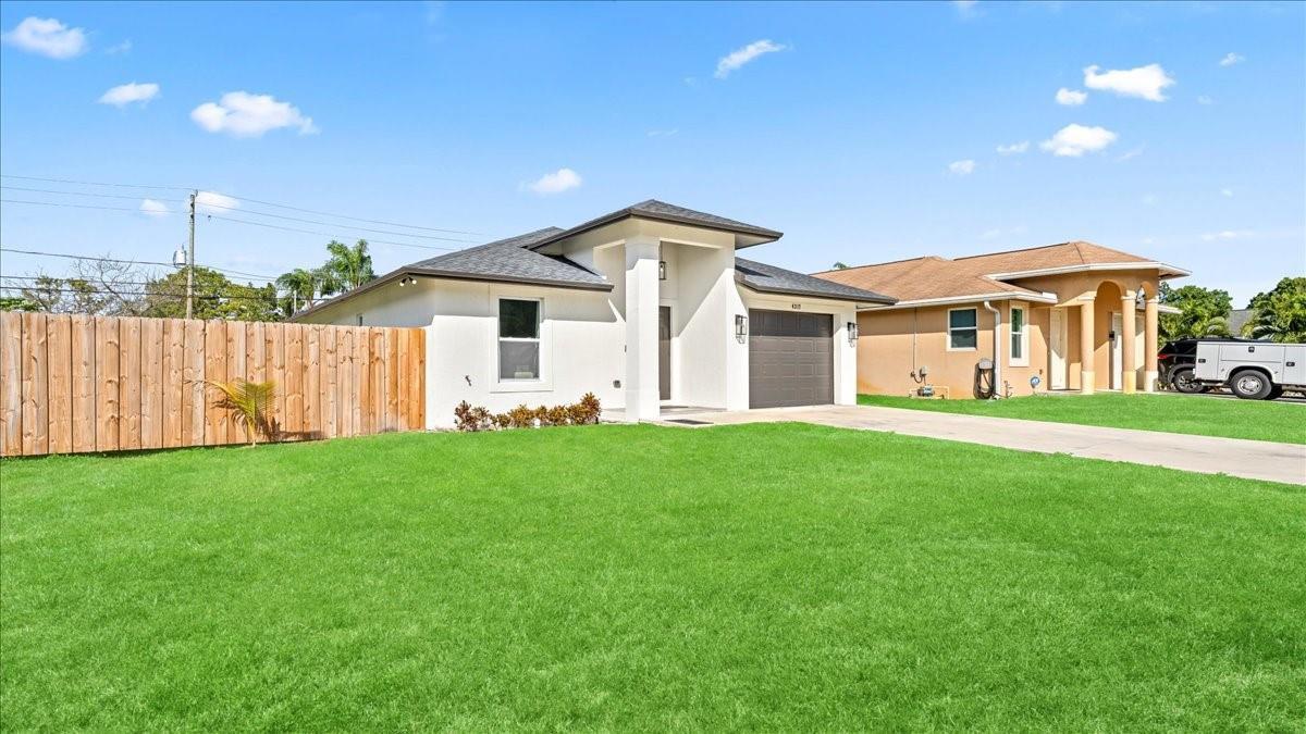 A modern white house with a gray garage and a wooden fence on a lawn — 4317 Vicliff Road, West Palm Beach FL 33406, WEST PALM BEACH, FL