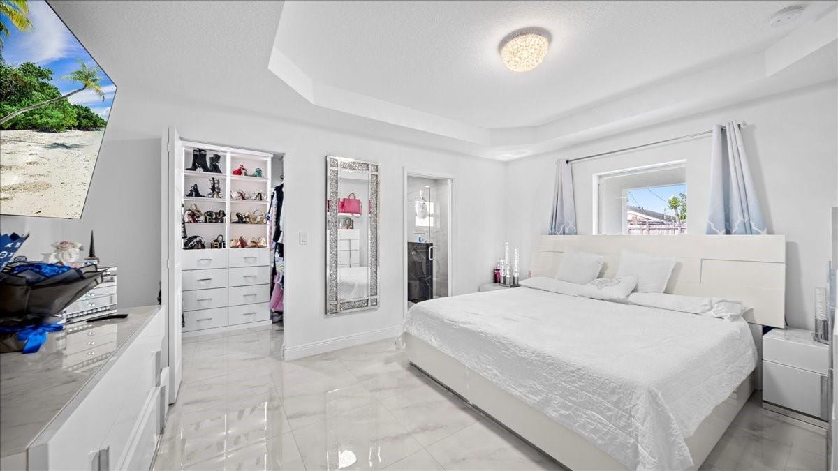 A bright, white-themed bedroom features a large bed, walk-in closet, and polished tile flooring — 4317 Vicliff Road, West Palm Beach FL 33406, WEST PALM BEACH, FL