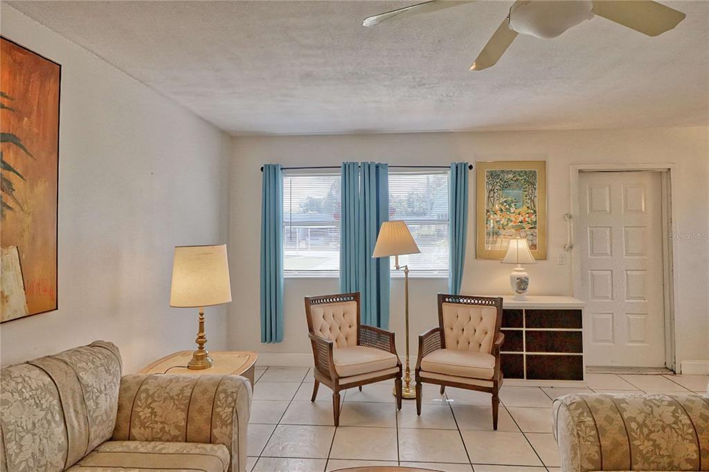 A living room features tiled floors, two armchairs, a sofa, and a ceiling fan — 101 CAMBRIDGE TRAIL UNIT 196, SUN CITY CENTER, FL