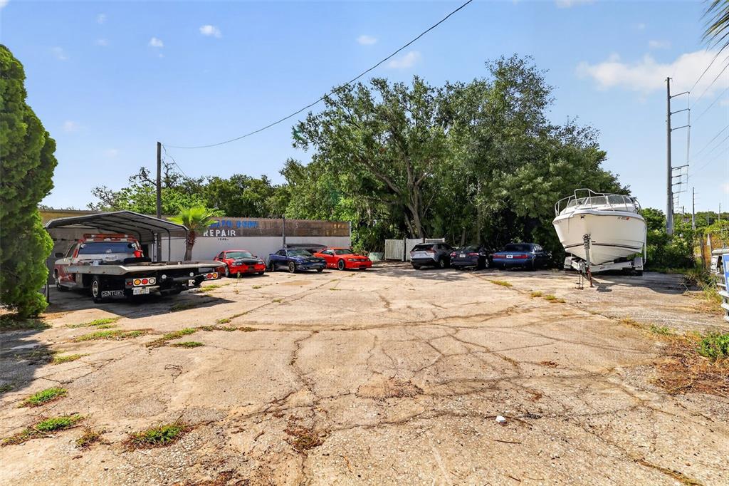 An outdoor lot features a repair shop building, several parked cars, and a boat — 1945 S US HIGHWAY 441, LADY LAKE, FL
