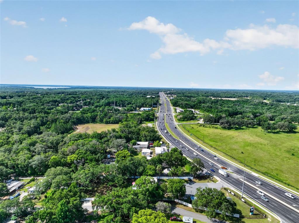 An aerial view shows a multi-lane highway cutting through a dense, green landscape — 1945 S US HIGHWAY 441, LADY LAKE, FL