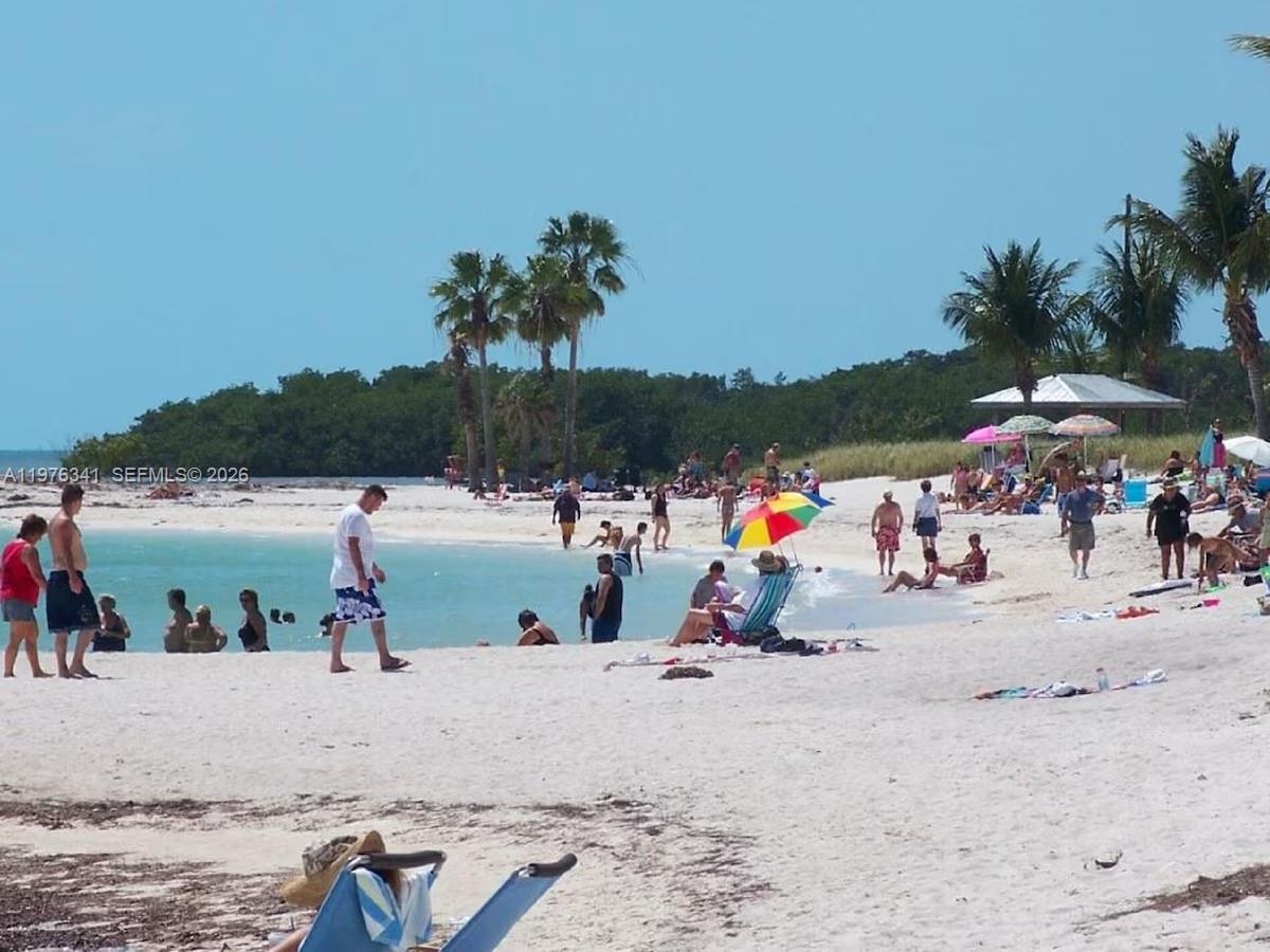 A sandy beach with people, palm trees, and a small pavilion in the background — 12400 Overseas Hwy, Marathon FL 33050, MARATHON, FL