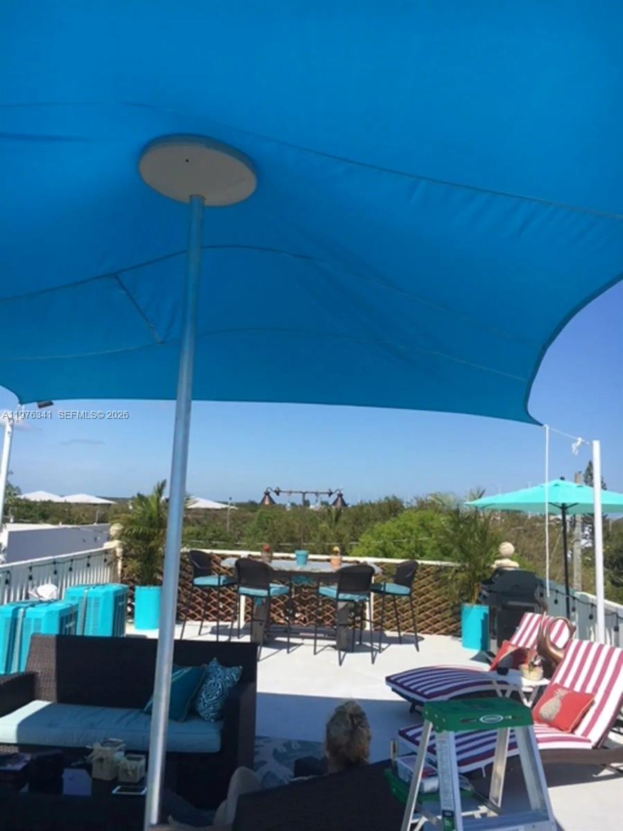 A rooftop patio features a blue shade sail, outdoor dining furniture, and lounge chairs — 12400 Overseas Hwy, Marathon FL 33050, MARATHON, FL