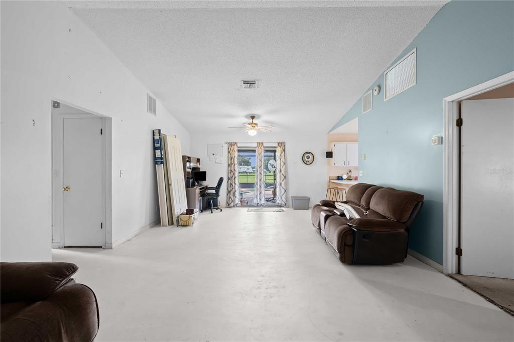 A living room with white walls, a brown sofa, and a sliding glass door — 348 CR 542E, BUSHNELL, FL
