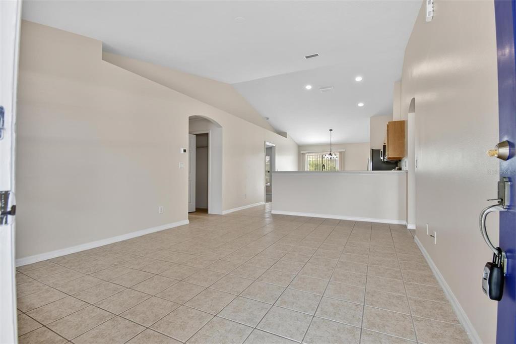 An open-concept living area features light-colored tile flooring, vaulted ceilings, and a kitchen pass-through — 83 LYNBROOK DRIVE UNIT A, PALM COAST, FL