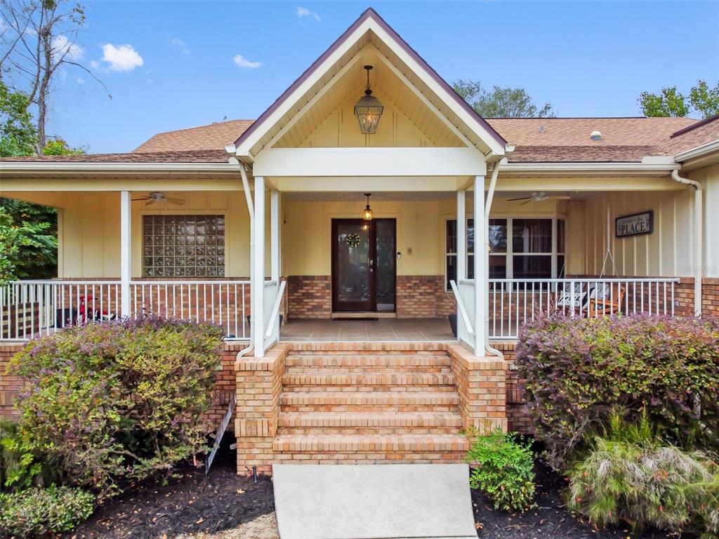 A front view of a house with a brick porch, stairs, and a gabled entryway — 5301 MERRIFIELD COURT, SPRING HILL, FL