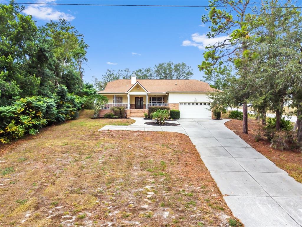 A single-story house with a tan exterior, a front porch, and a concrete driveway — 5301 MERRIFIELD COURT, SPRING HILL, FL