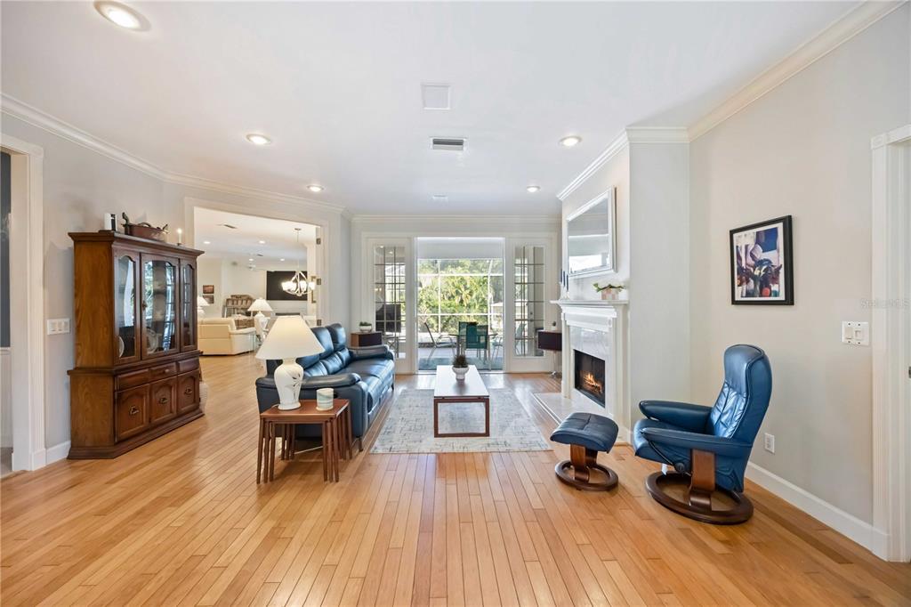 A living room with hardwood floors, a fireplace, a blue leather sofa, and glass doors — 1860 CITRON STREET, PORT CHARLOTTE, FL