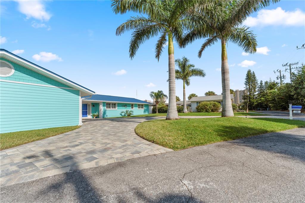 A teal house with a blue metal roof features a paved driveway and palm trees — 118 CORAL WAY, PORT ORANGE, FL