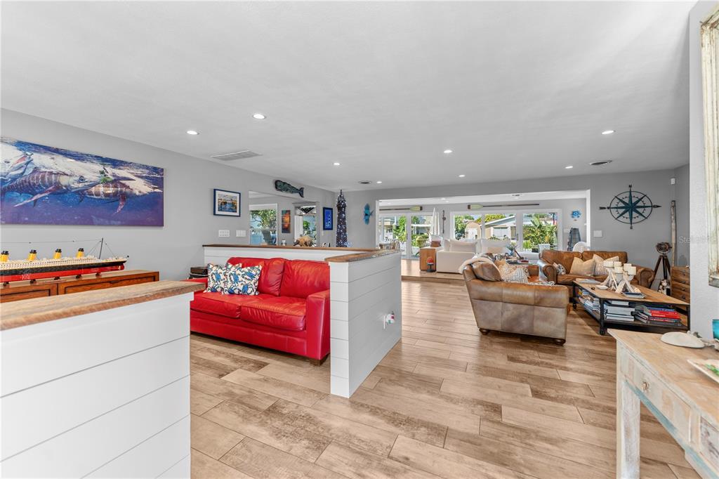 A living room features a red sofa, wood-look tile flooring, and a partial shiplap wall — 118 CORAL WAY, PORT ORANGE, FL