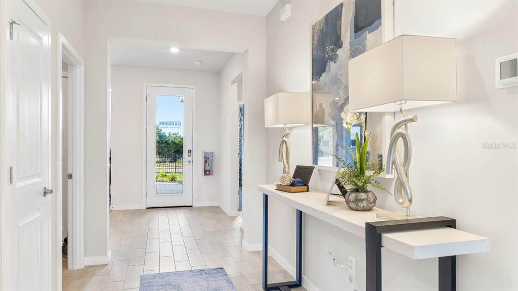 A bright entryway features light wood-look tile flooring, a console table, and a glass-paneled door — 16301 STONEFRONT LANE, PORT CHARLOTTE, FL