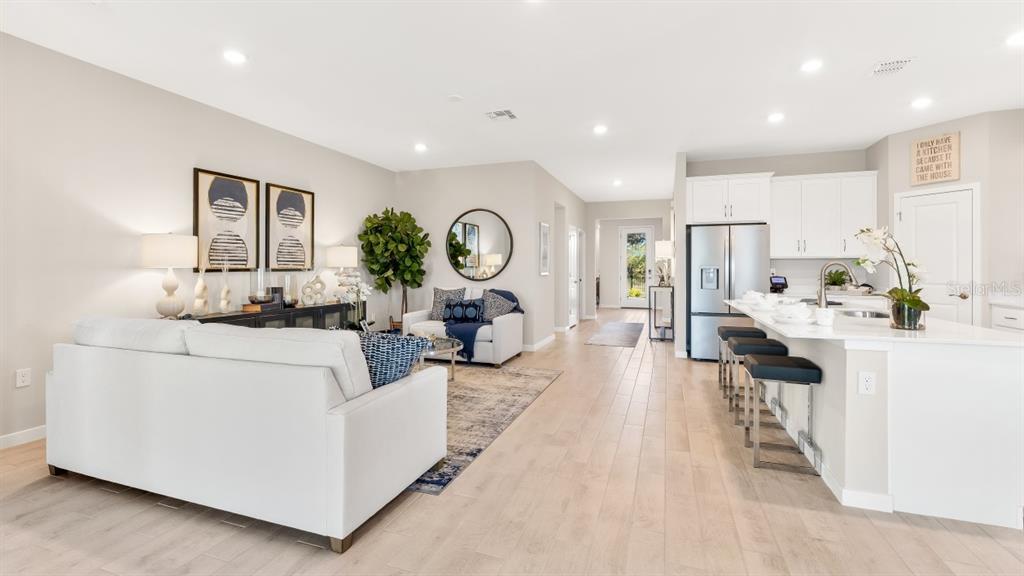 An open-concept living room and kitchen featuring light wood flooring and white cabinetry — 16301 STONEFRONT LANE, PORT CHARLOTTE, FL