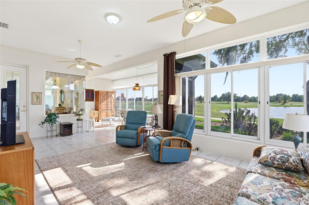 A sunroom features tile floors, two blue armchairs, and large windows overlooking a golf course — 237 GOLF VISTA DRIVE, DAVENPORT, FL