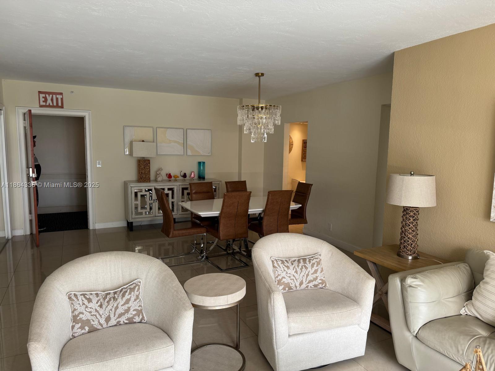 A dining area with a chandelier and a living space with armchairs and tile flooring — 3801 S Ocean Dr # 14V, Hollywood FL 33019, HOLLYWOOD, FL