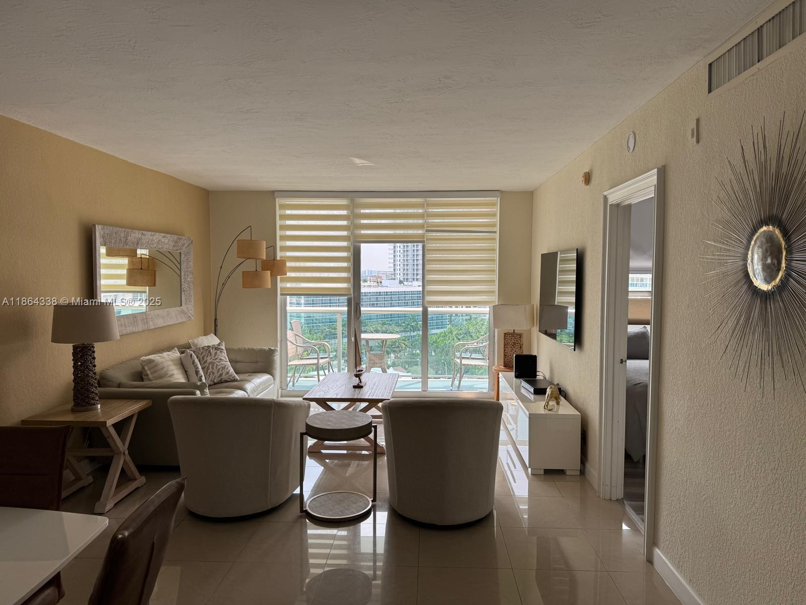 A living room features light-colored furniture, a balcony with city views, and tile flooring — 3801 S Ocean Dr # 14V, Hollywood FL 33019, HOLLYWOOD, FL