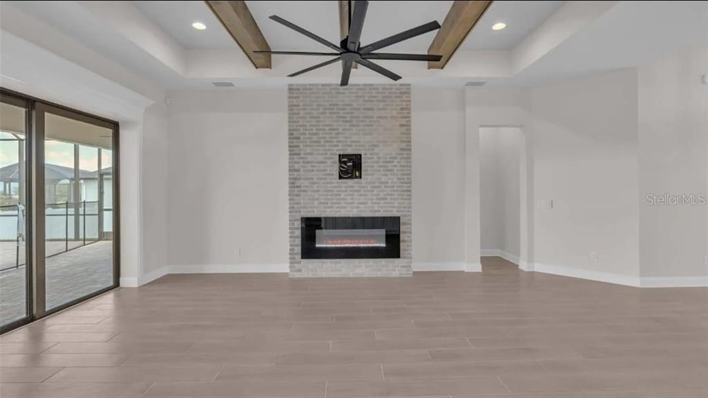 A modern single-story house with a three-car garage, stone accents, and a paved driveway — 6980 BENTRIDGE DRIVE, LAKELAND, FL