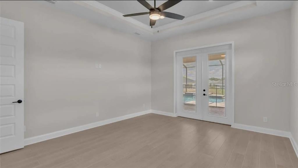 A modern kitchen features white cabinetry, a large quartz island, and three glass pendant lights — 6980 BENTRIDGE DRIVE, LAKELAND, FL
