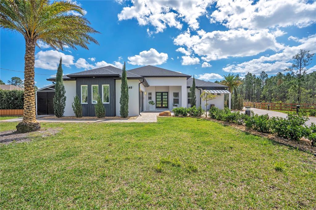 A modern single-story house with a white facade, dark metal siding, and a palm tree — 19240 LANSDOWNE STREET, ORLANDO, FL