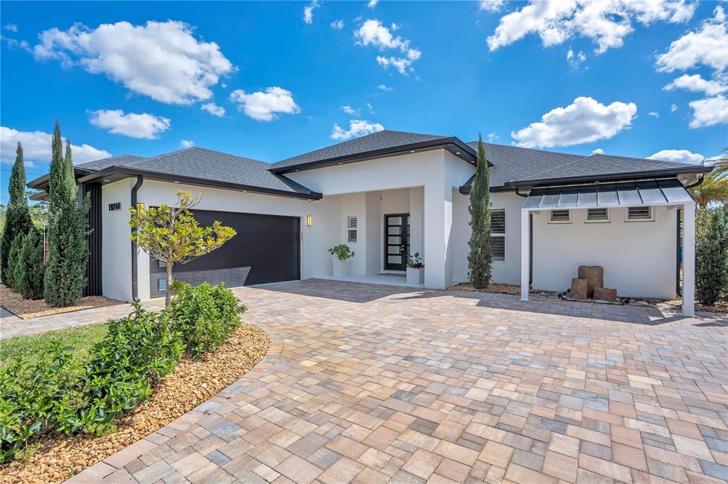 A modern single-story house features a paved driveway, a black garage door, and white stucco — 19240 LANSDOWNE STREET, ORLANDO, FL