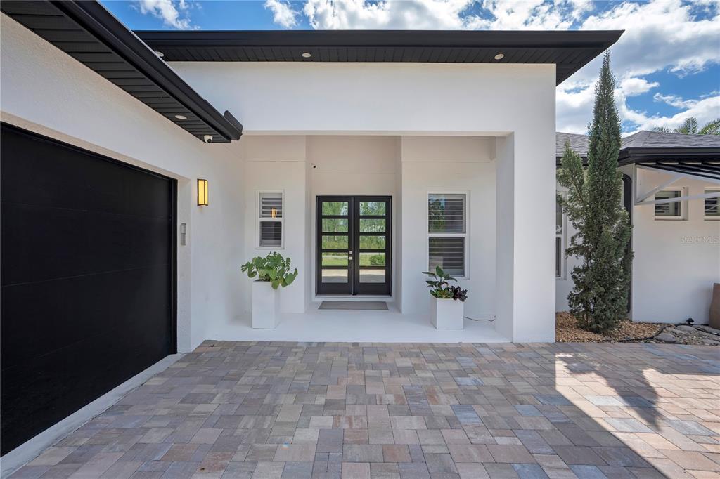 The exterior of a modern white house features a black double door and garage door — 19240 LANSDOWNE STREET, ORLANDO, FL
