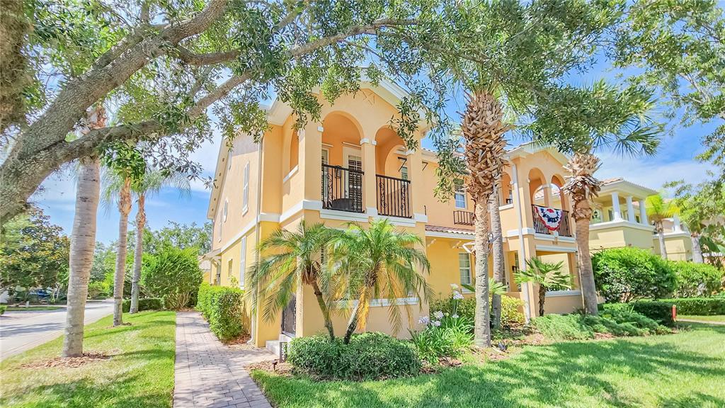 A two-story yellow stucco building with arched balconies and palm trees in the front yard — 8523 LEATHERLEAF LANE, ORLANDO, FL